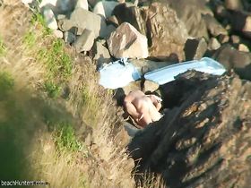 Молодая парочка занимается сексом на каменном пляже пока их снимают на камеру