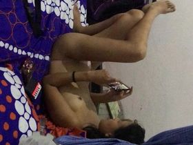 Телка с маленькими сиськами голенькой лежит на кровати и смотрит порно